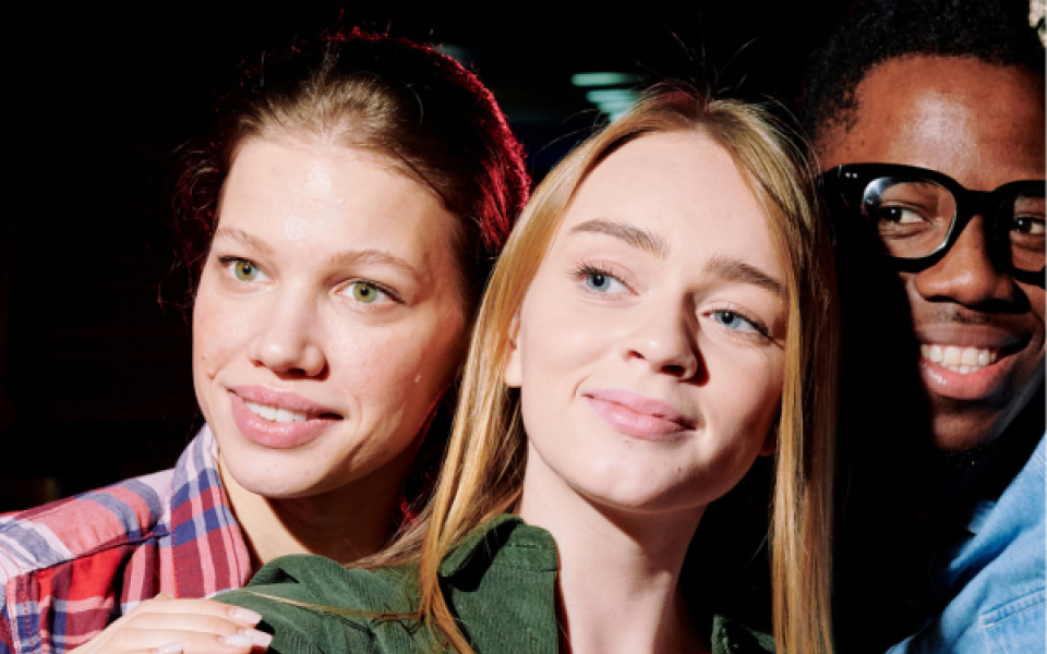 Two women and one man looking at a camera 