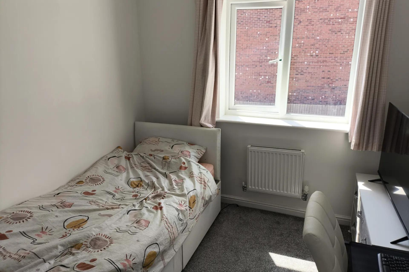 Bedroom with a single bed, chest of drawers and TV