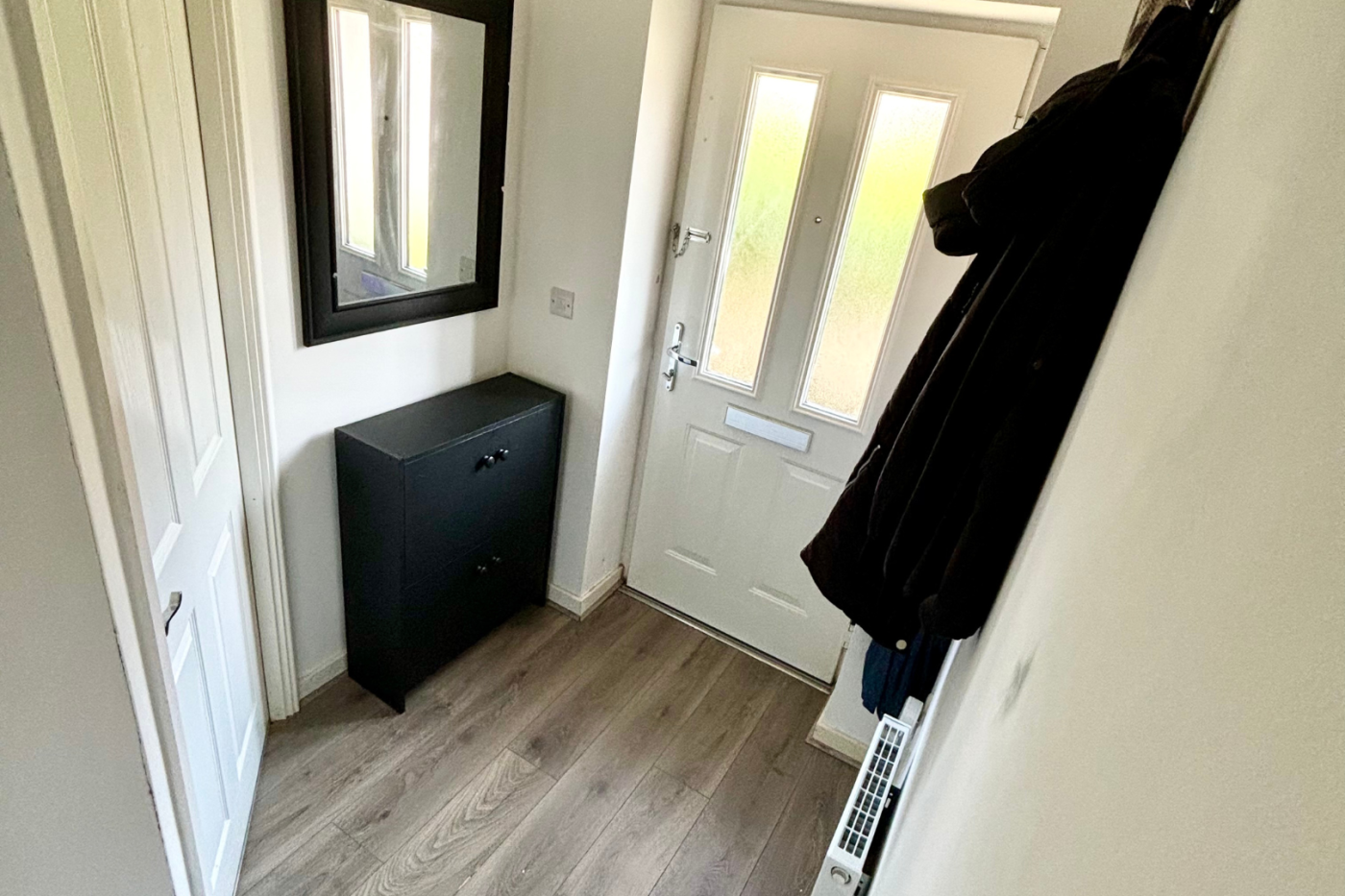 Entrance hallway with coats hanging up and a mirror by the door