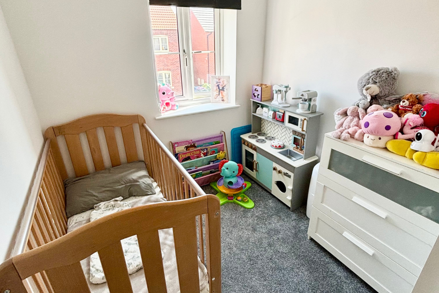 small bedroom with a cot, chest of drawers and toys