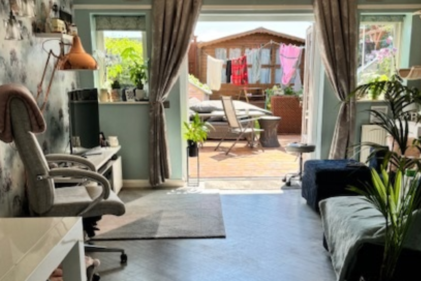 A photo of a living room with the doors open showing decking and the garden