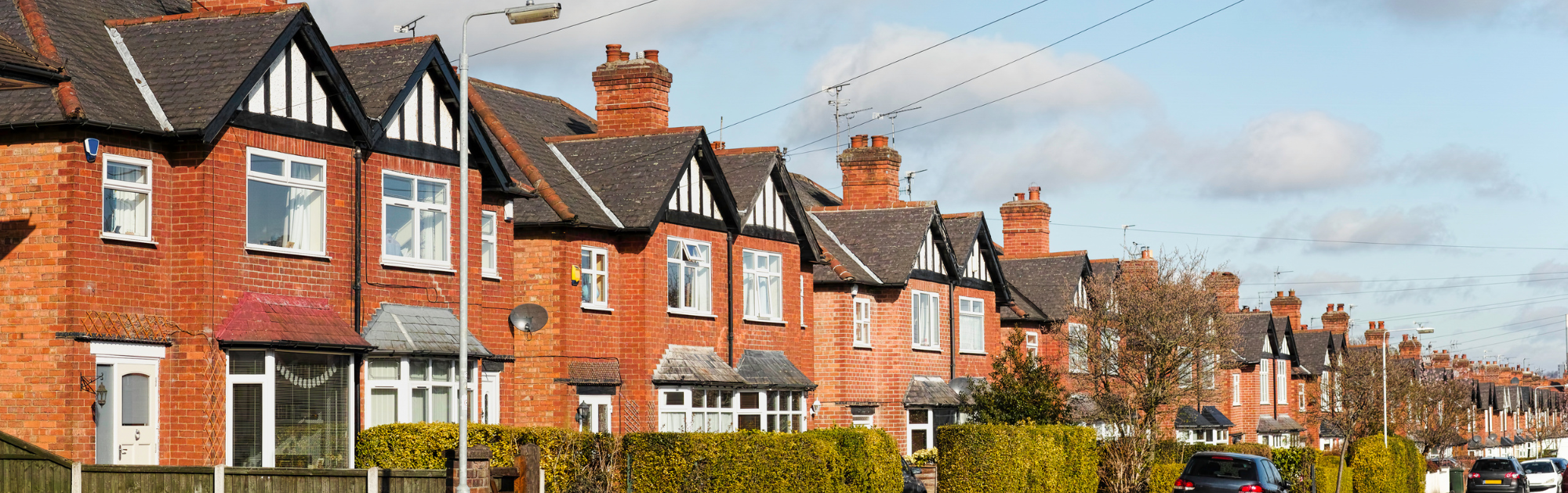 A street of terraced houses with parked cars on the road