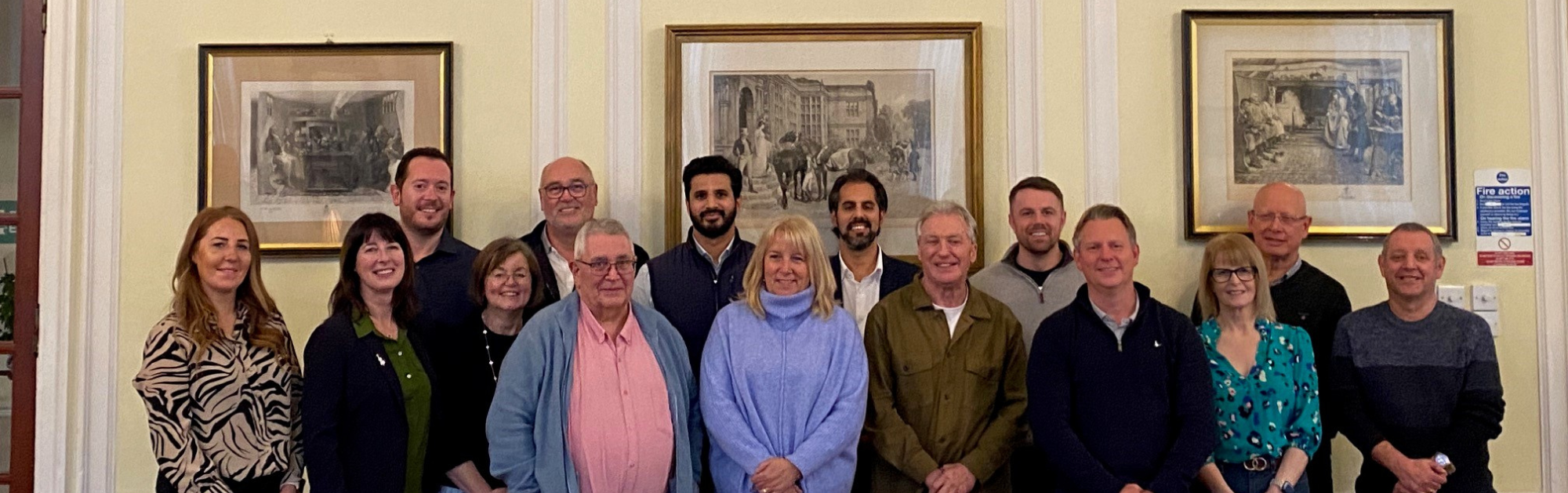 A group of people smiling stood in a row