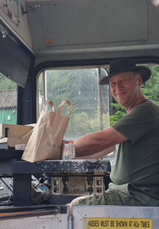 A man behind the wheel of a bus smiling