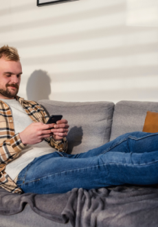 A man on his phone sat on the sofa