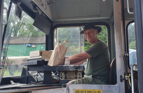 A man behind the wheel of a bus smiling