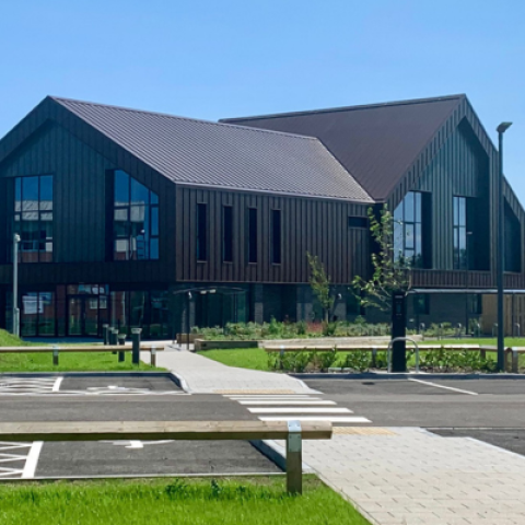 A picture of a building with a car park in the foreground on a sunny day