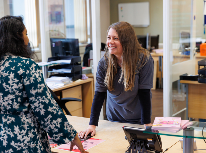 Two women talking and smiling over a reception desk