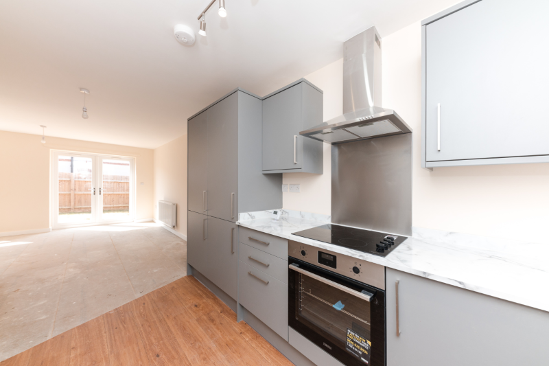 Kitchen worktops and living room space with patio doors at the far end