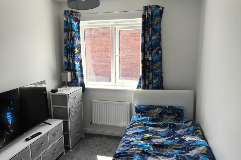 Bedroom with a single bed, chest of drawers and TV