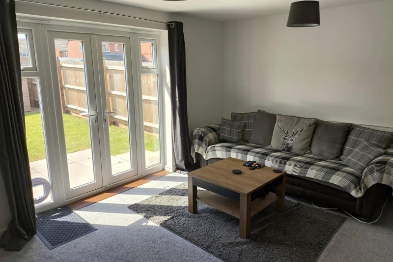 living room with a sofa, coffee table and patio doors out into the garden