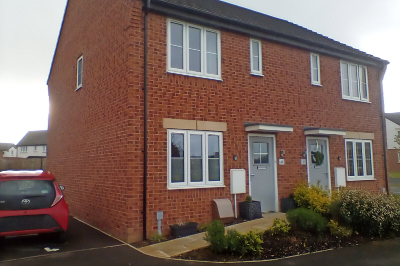 front of a semi detached house with a car parked on the drive