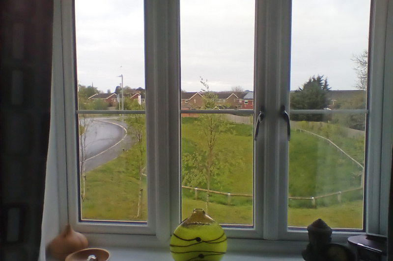 View from an upstairs window onto a field and a road