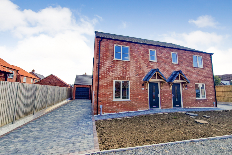 Front of a semi detached house with a drive and garage