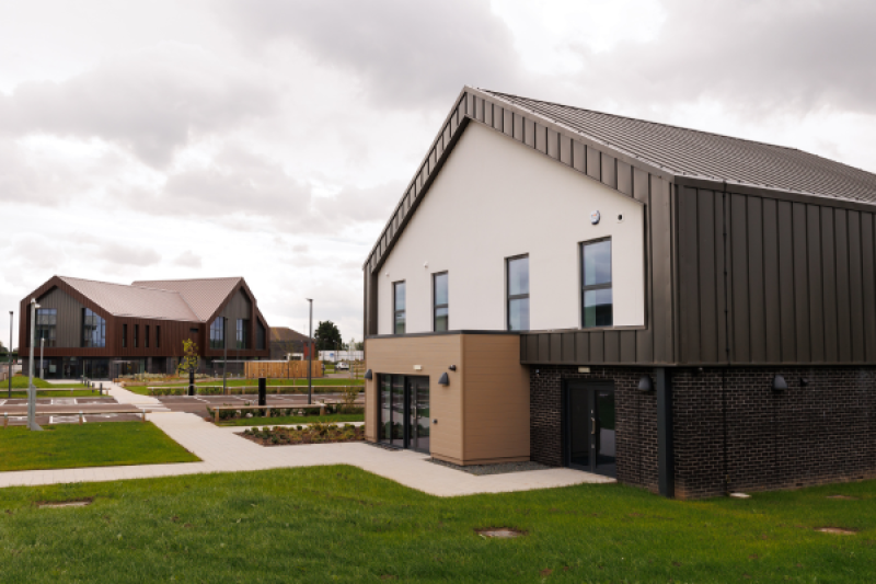 One building in the foreground and a second in the background with greenery and grey skies