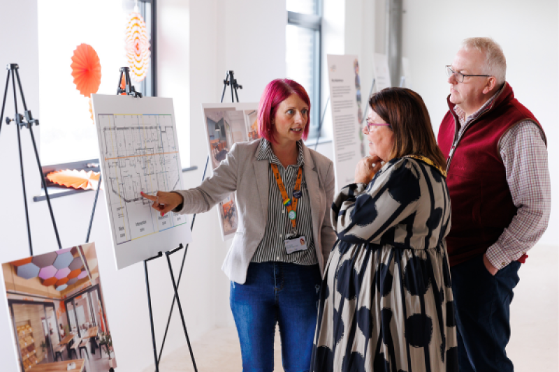 Three people talking and looking at a board