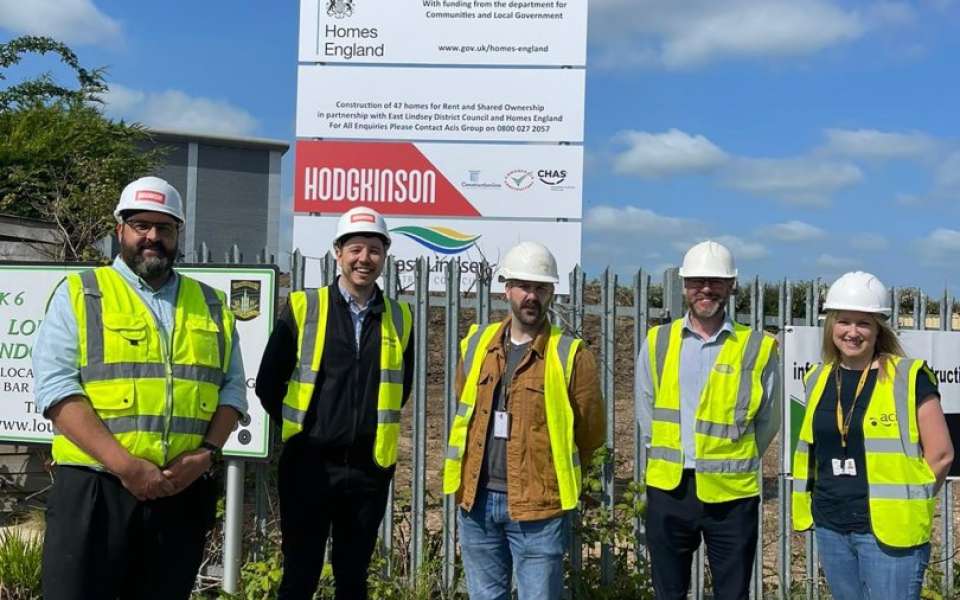 A group of people stood in hard hats and a high vis