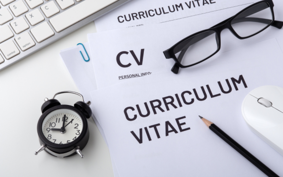 A picture of a blank CV with a pencil, computer mouse, a pair of glasses and a clock