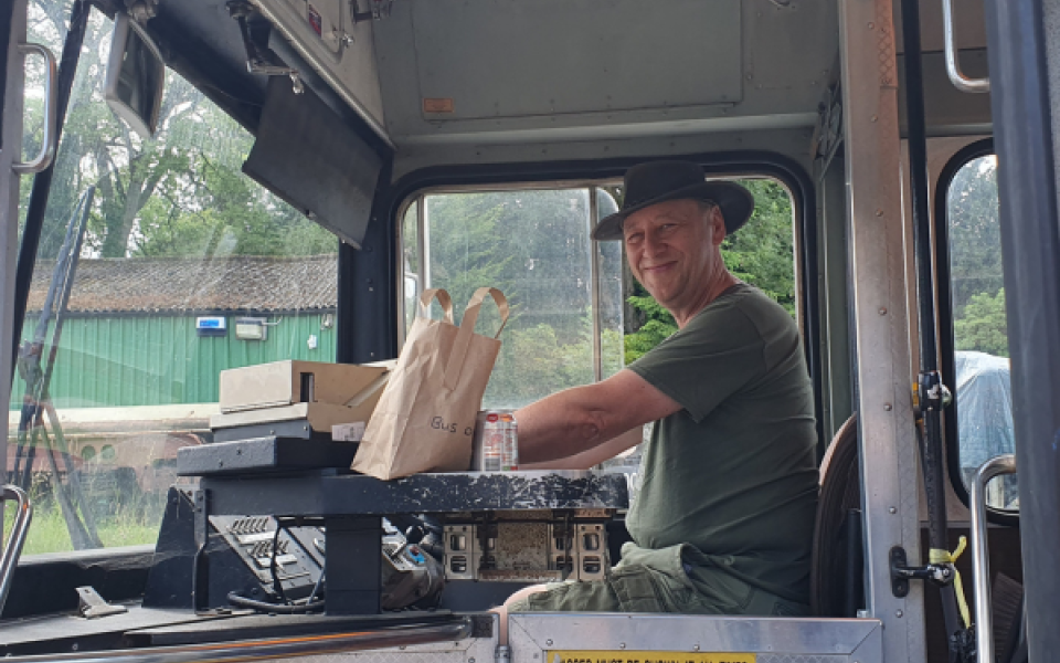 A man behind the wheel of a bus smiling