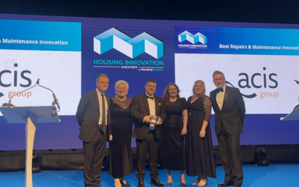 A group of people stood on a stage smiling with an award