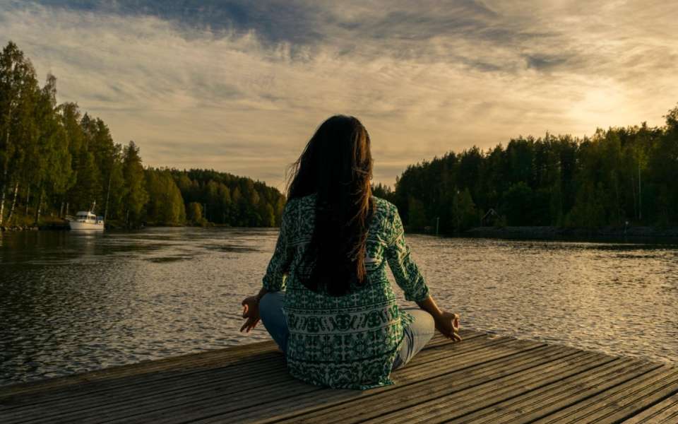 Woman meditating looking over lake and trees