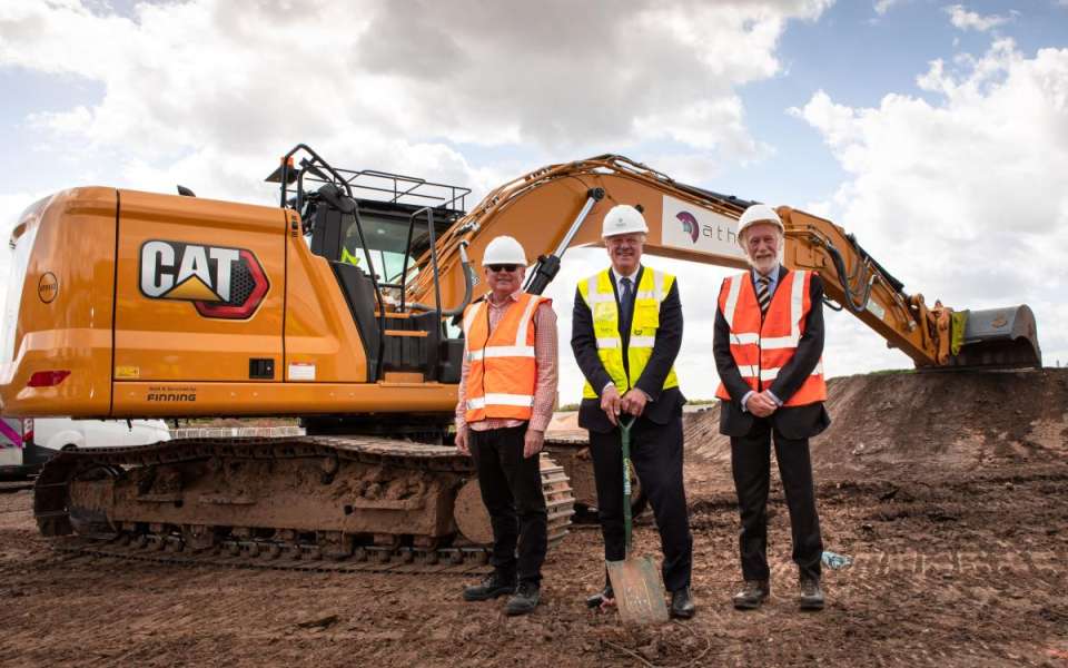 3 people standing in front of a large digger