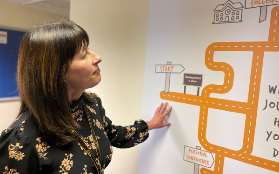 A woman looking at a road map on a wall.