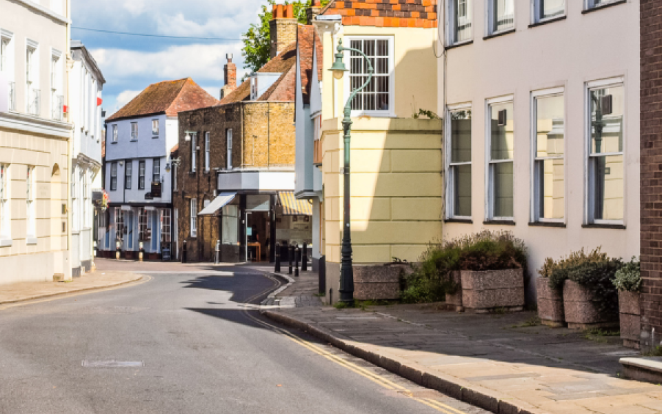 A generic picture of a town showing a road with double yellow lines and some buildings