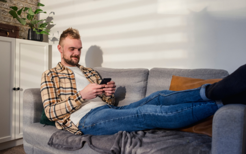 A man on his phone sat on the sofa