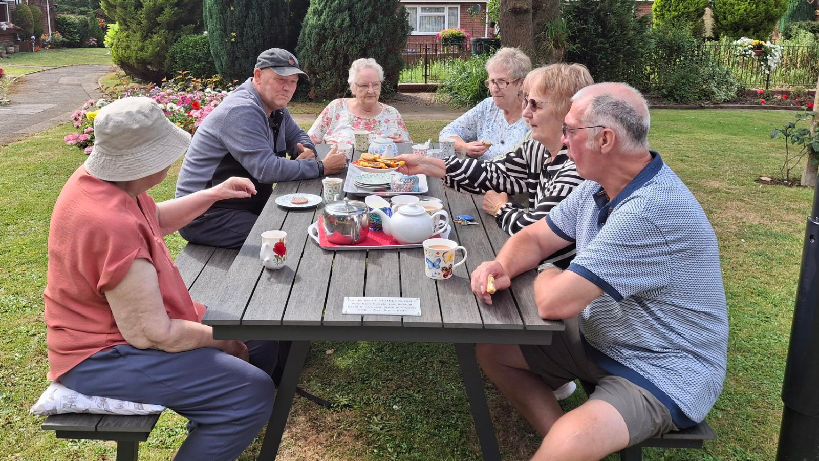 A picture of the residents enjoying tea and biscuits whilst sat at their bench